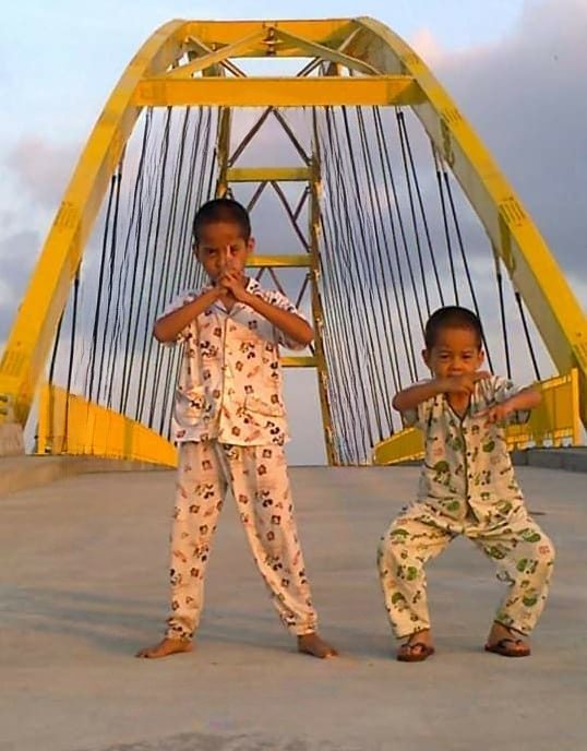 Rafiq dan Muslih waktu kecil, berpiyama, berpose di jembatan kuning
